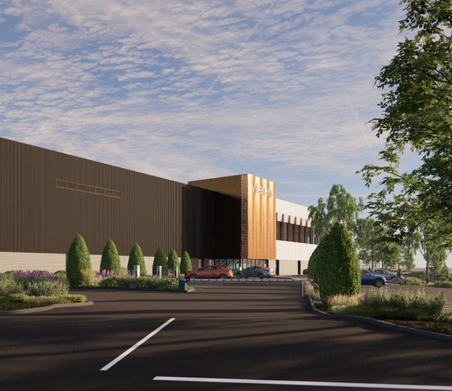 A cgi of the Waters Corporation building, it's a view of the road coming up to a rectangular dark grey building a copper coloured extension above the entrance with the Waters logo at the top.